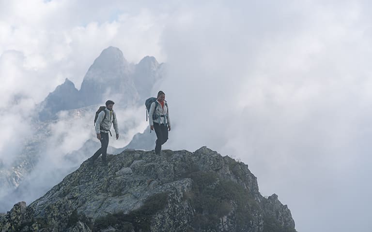 Man & Women hiking up a mountain wearing RealFleece™ Merino High Pile Long Sleeve Zip Jacket.