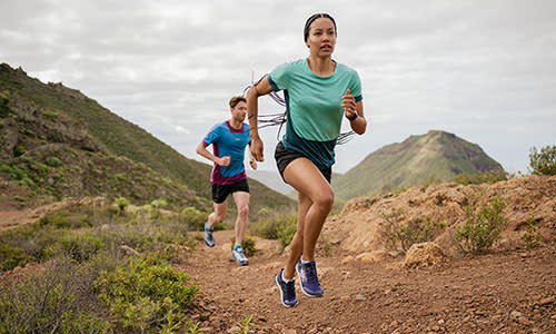 Woman and man running up a hill wearing icebreaker zoneknit merino t-shirts and shorts