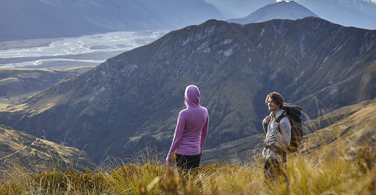 Man and Woman hiking wearing Merino Quantum III Long Sleeve Zip Hoodies in Cosmic/Grape and Metro Heather