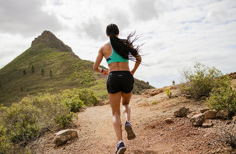 Woman running up a hill wearing icebreaker merino shorts and sports bra