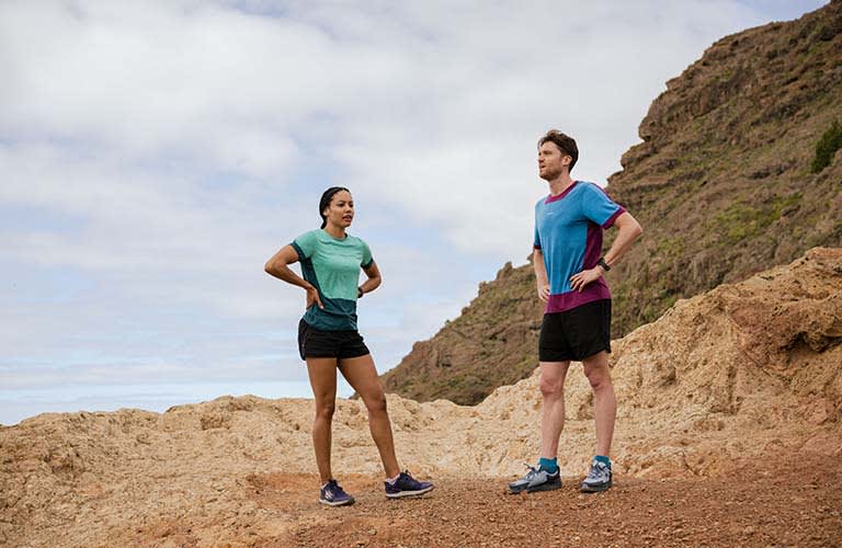 Woman and man at top of mountain wearing icebreaker merino t-shirts and merino shorts