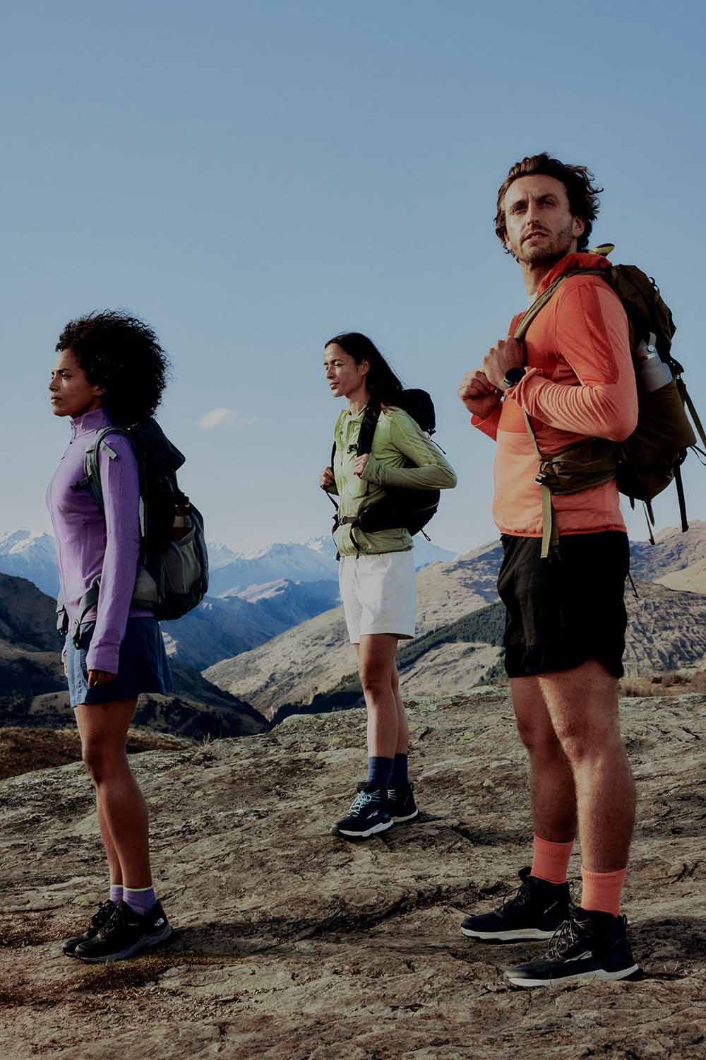 Three hikers standing at top of mountain wearing icebreaker descender sweatshirts