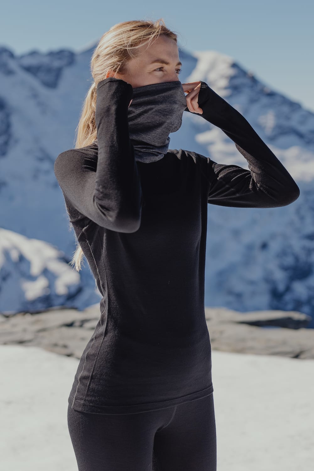 A women wearing black Oasis base layer stands on the mountain.