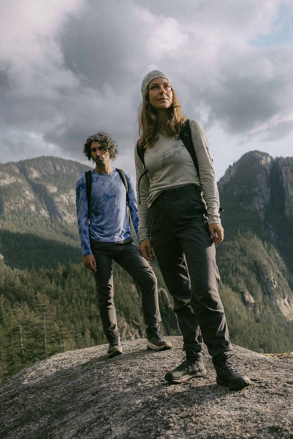 Woman and man standing on top of a rock wearing icebreaker merino cloud dye base layer thermal tops