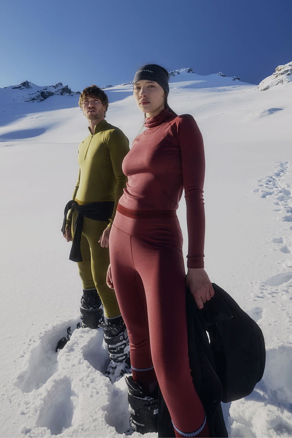 Man and woman standing in snow waring icebreaker merinofine base layer thermal top and merino leggings