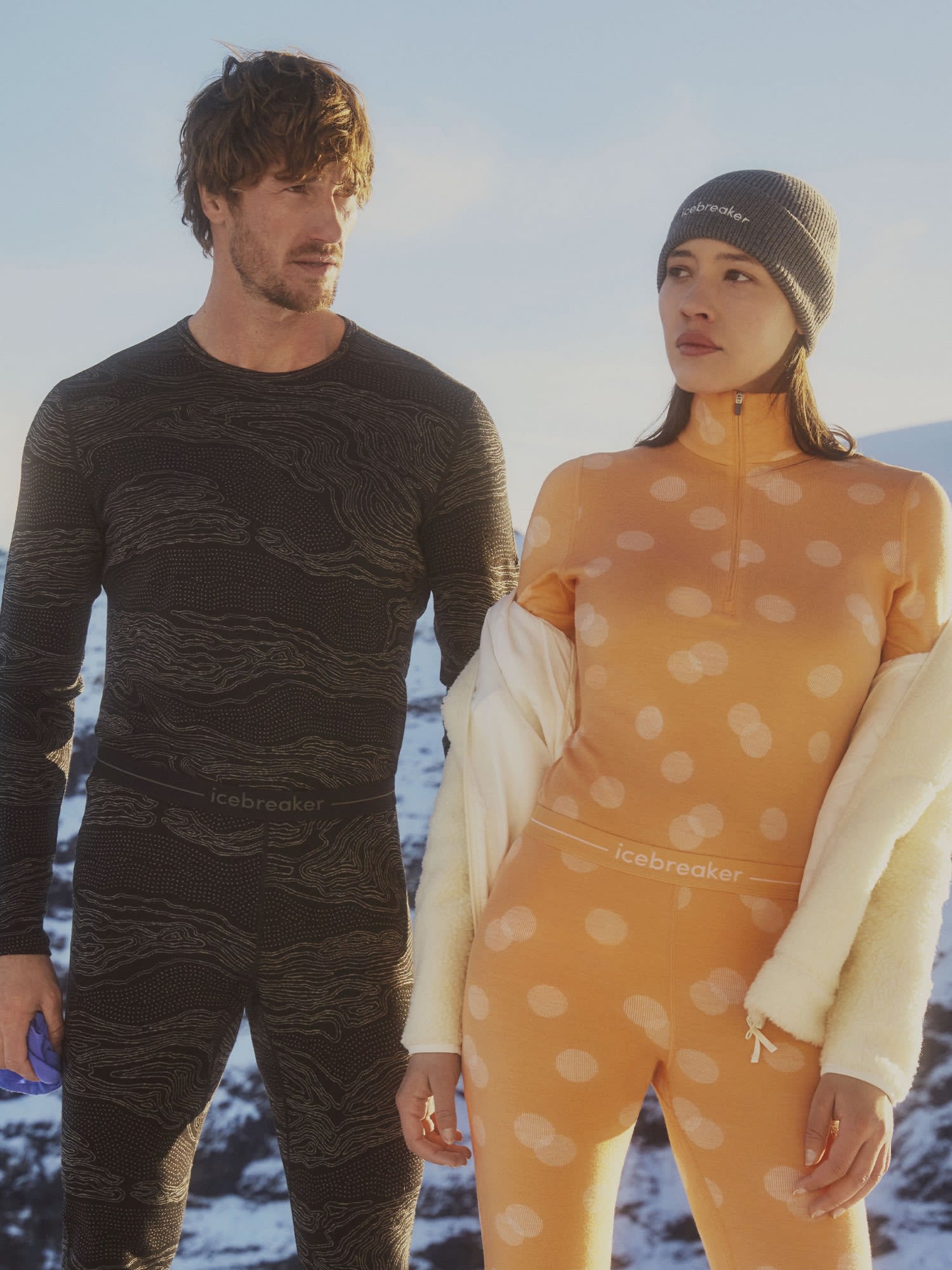 Man and woman standing in the snow wearing icebreaker vertex base layer merino thermal tops and merino thermal bottoms