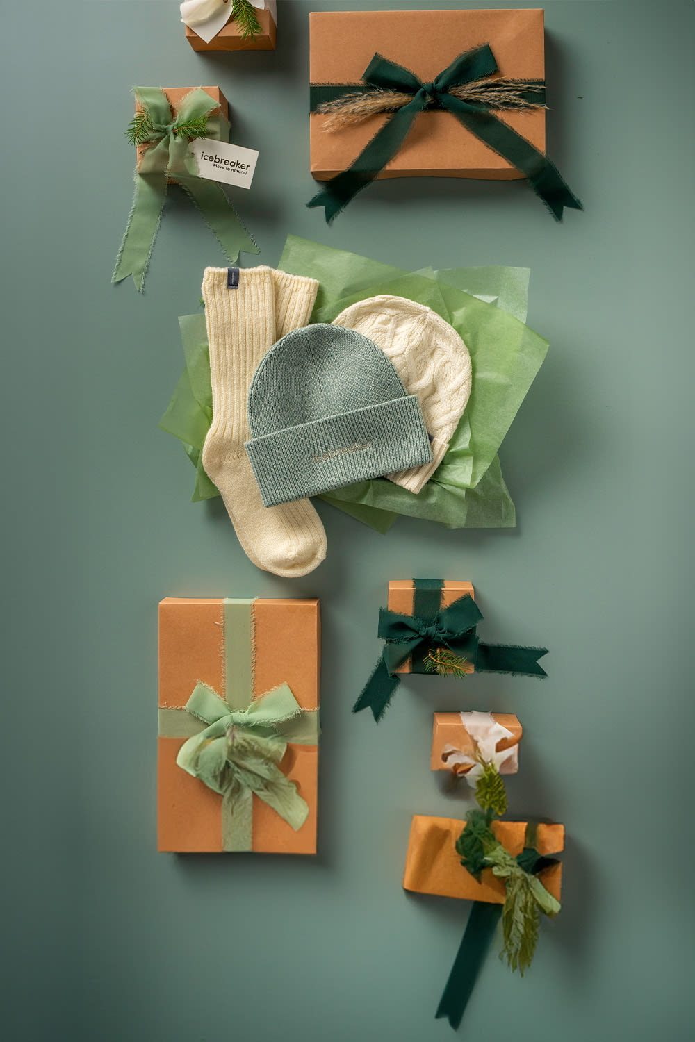 Gifting image theme. Gifts as well as small icebreaker products such as hats and socks laid out on a green background. 