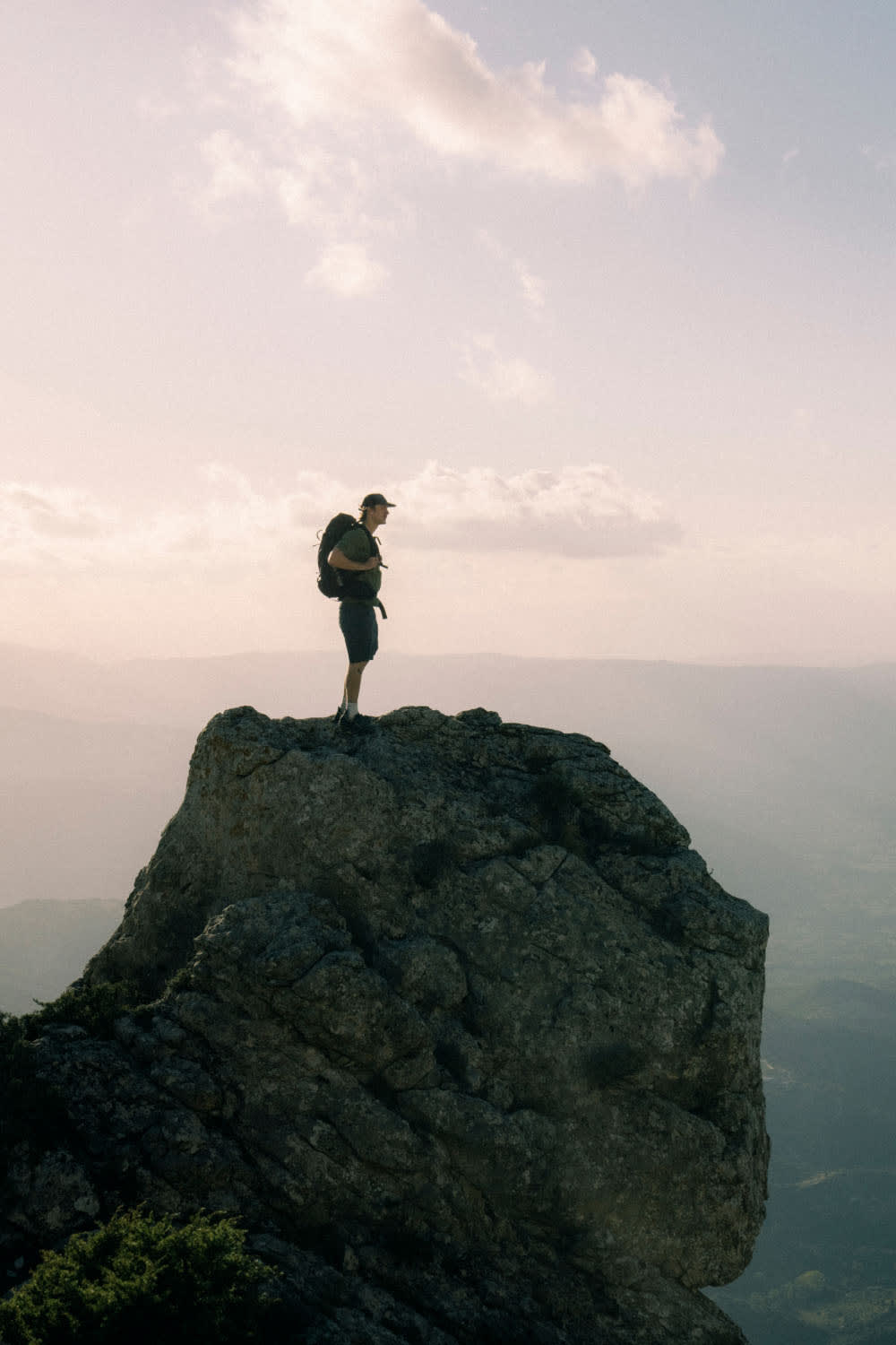 Man standing on rocky mountain top wearing icebreaker merino t-shirt and merino shorts