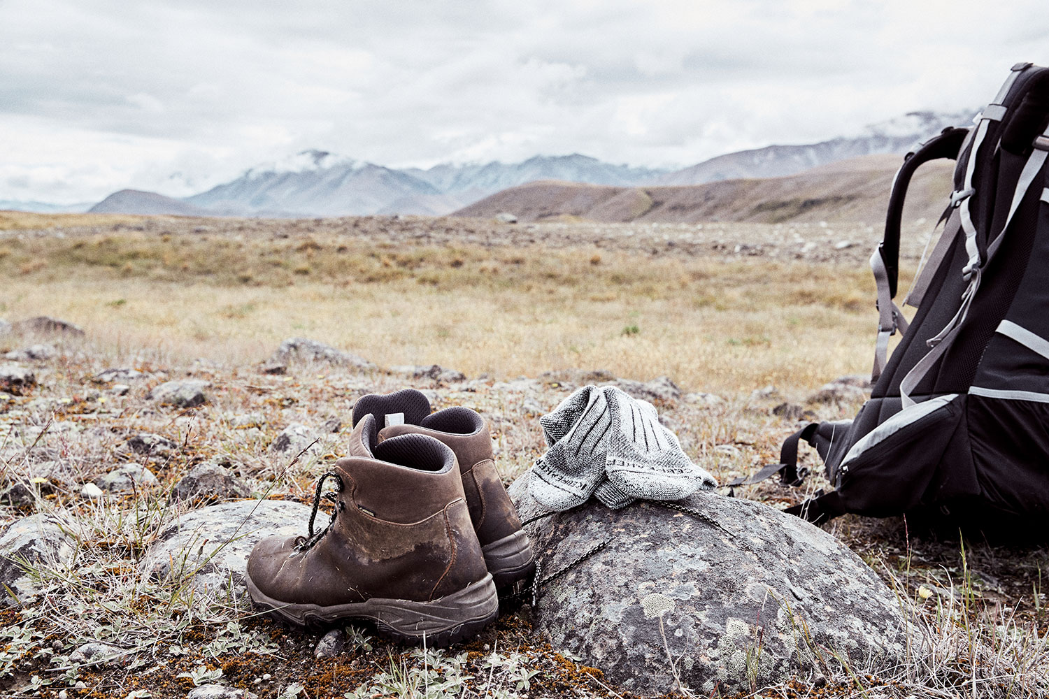 chaussettes de randonnée brise-glace posées sur un rocher à côté de chaussures de randonnée et d'un sac de randonnée