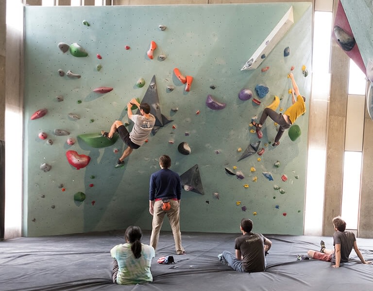 Two climbers bouldering and four watching on