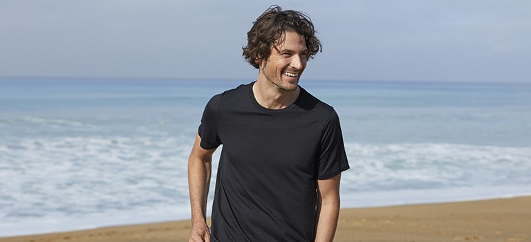 Homme sur la plage vêtu d'un t-shirt mérinos sphère brise-glace noir