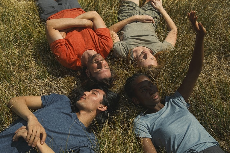 Quatre personnes allongées sur l'herbe portant des t-shirts brise-glace cool-lite