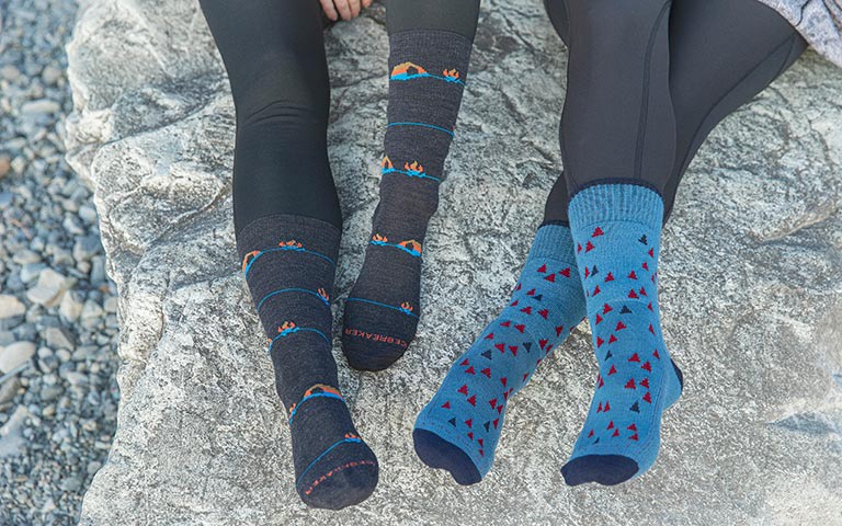 Deux personnes assises sur un rocher qui portent des chaussettes de randonnée icebreaker