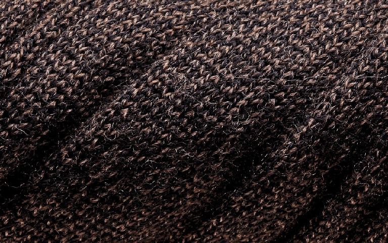 Fine merino fibres on a knitwear sweater in dark brown colour.