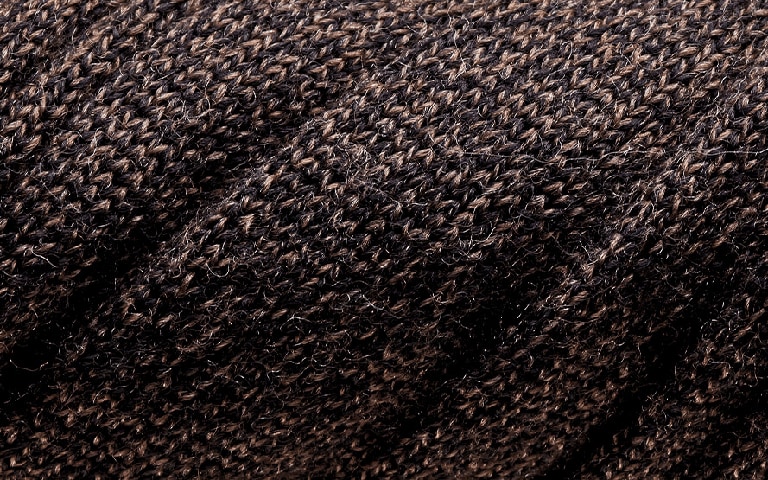 Fine merino fibres on a knitwear sweater in dark brown colour. 