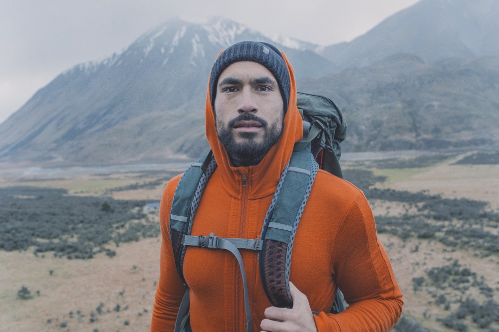 man hiking wearing orange quantum hoodie and merino tuque