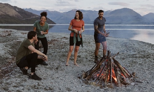 Four people standing around a campfire