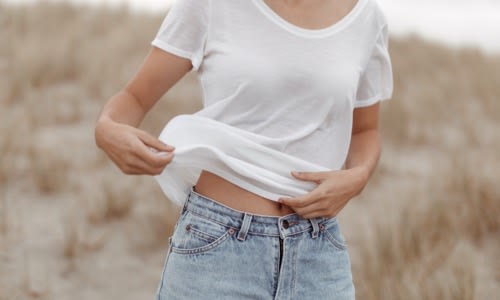 Woman standing in grass field wearing white icebreaker merino short sleeve t-shirt