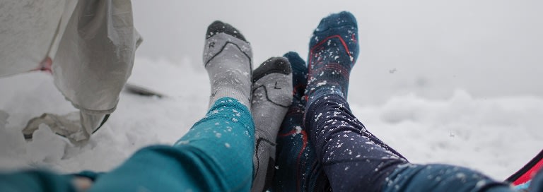 Deux personnes allongées dans une tente portant des chaussettes de ski en mérinos brise-glace