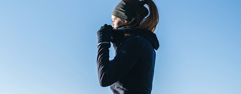 Woman standing outside wearing icebreaker gloves and headband