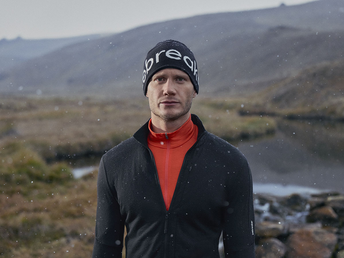 Man hiking wearing icebreaker merino base layer, merino half zip and merino beanie