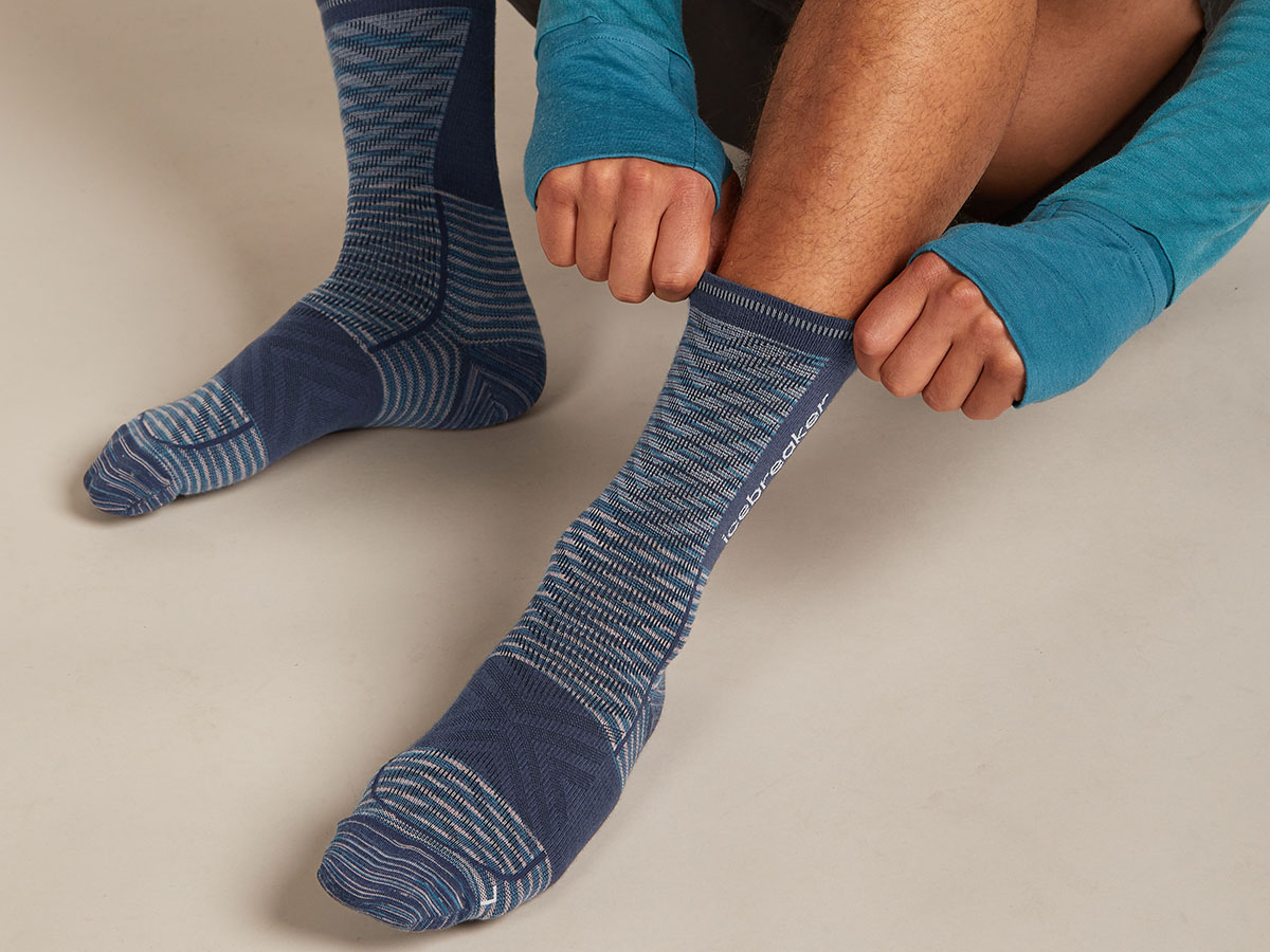 Un homme enfile des chaussettes de course en mérinos Icebreaker