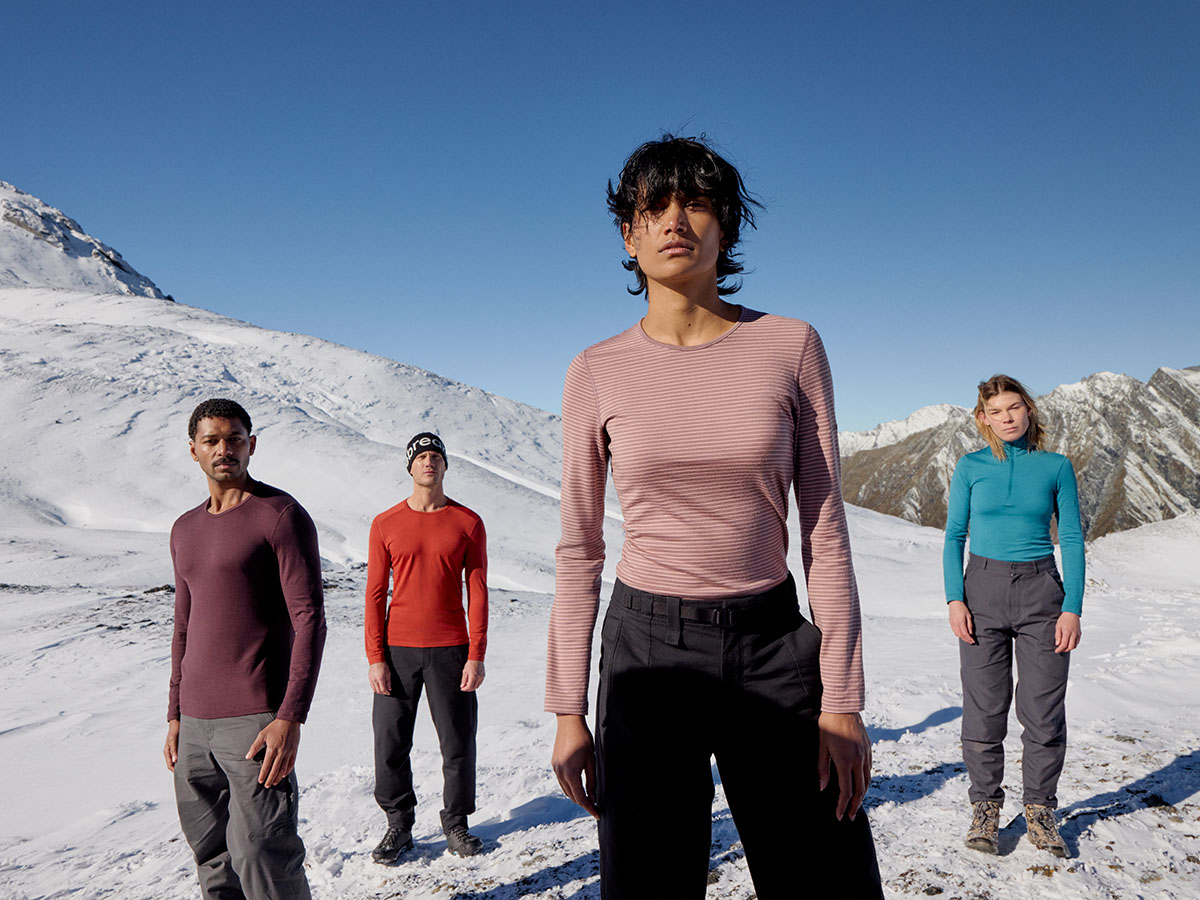 Quatre personnes debout dans la neige portant des hauts thermiques de base en mérinos Icebreaker Oasis